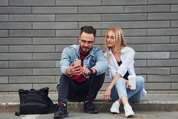 Jeune homme élégant avec une femme en vêtements décontractés assis à l'extérieur ensemble Conception d'amitié ou de relations