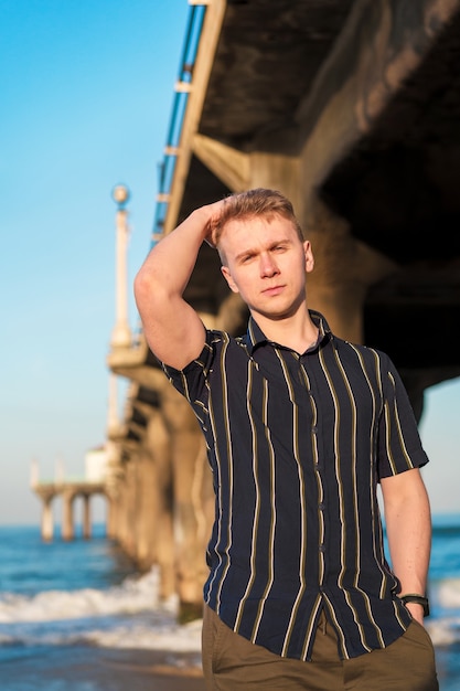 Jeune homme élégant pose près de la jetée de Manhattan Beach à Los Angeles en Californie
