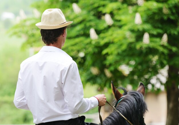 Jeune homme élégant prenant un cheval sur la campagne