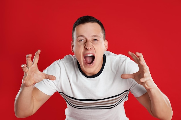 Jeune homme émotif posant sur fond rouge