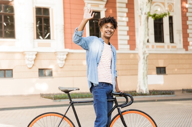 Jeune homme émotionnel dans la rue à l'extérieur à pied avec vélo