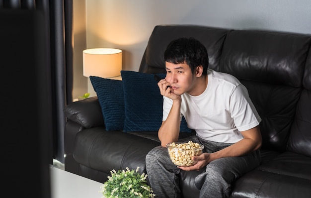 Jeune homme ennuyé devant la télé sur un canapé la nuit