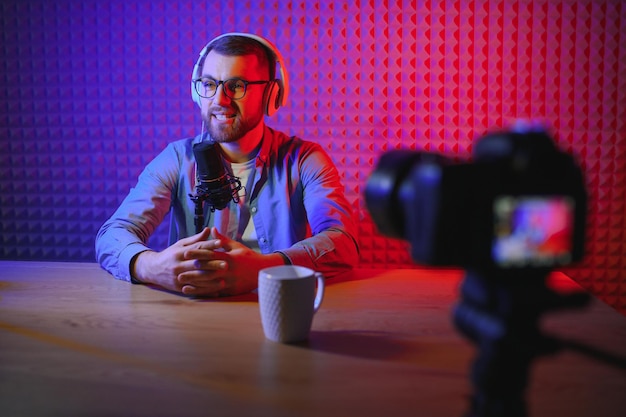 Jeune homme enregistrant ou diffusant un podcast à l'aide d'un microphone dans son petit studio de diffusion Créateur de contenu