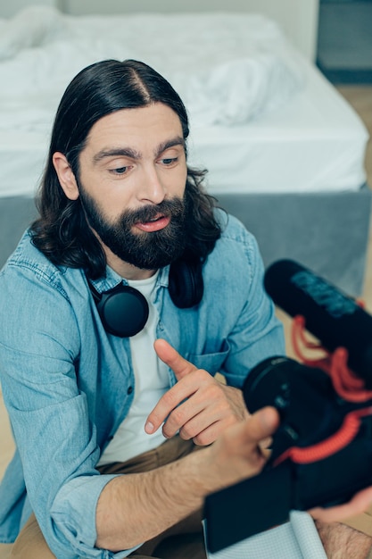 Jeune homme enregistrant son discours sur une vidéo et utilisant une caméra moderne avec un microphone