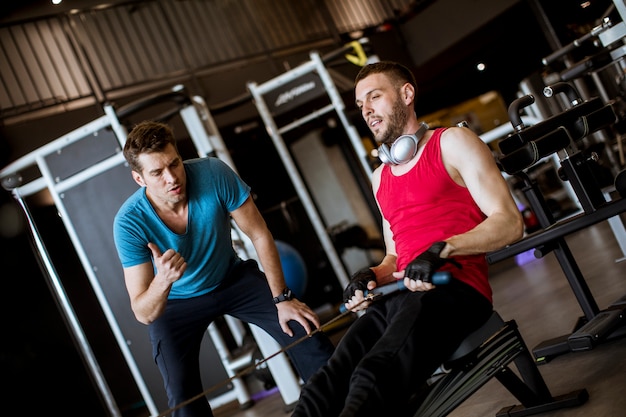 Jeune homme avec entraîneur faire des exercices dans le gymnase