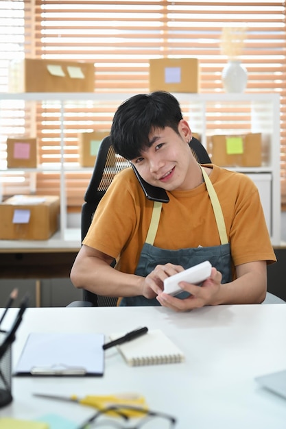 Jeune homme entrepreneur de petite entreprise confirmant les commandes du client sur un téléphone intelligent