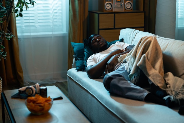 Un jeune homme épuisé s'est endormi sur un canapé confortable dans le salon d'un homme en manque d'énergie