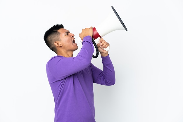 Jeune homme équatorien isolé sur fond blanc criant à travers un mégaphone pour annoncer quelque chose en position latérale