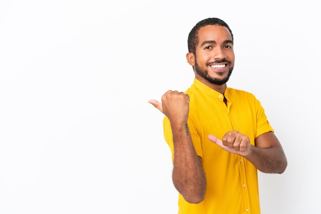 Jeune homme équatorien isolé sur fond blanc pointant vers le côté pour présenter un produit