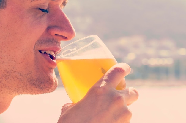 Un jeune homme essaie de boire de la bière tôt le matin sur la plage