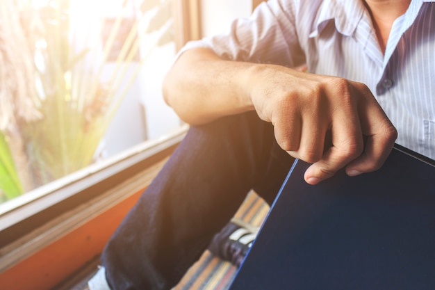 Jeune homme est assis en train de lire à la fenêtre dans la chambre