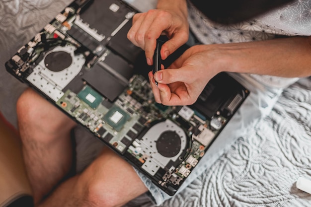 Un jeune homme est en train de changer la pâte thermique sur un ordinateur portable