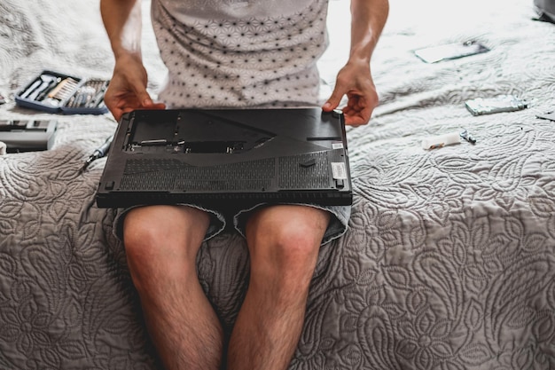 Un jeune homme est en train de changer la pâte thermique sur un ordinateur portable