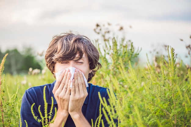 Un jeune homme éternue à cause d'une allergie à l'ambroisie