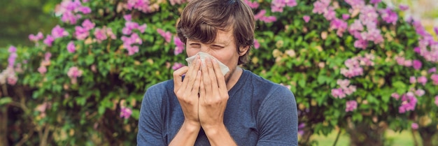 Jeune homme éternue à cause d'une allergie au pollen BANNIÈRE format long