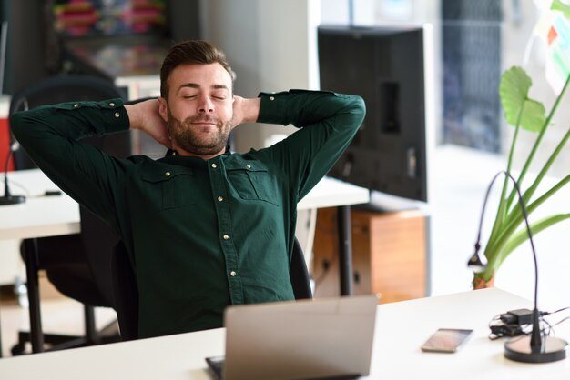 Jeune homme étudiant avec ordinateur portable sur un bureau blanc.