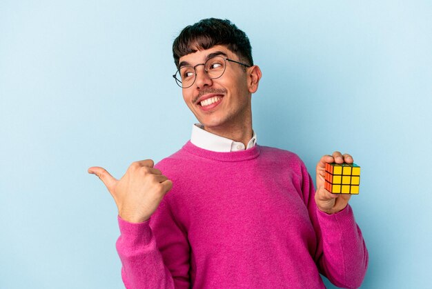 Jeune homme étudiant de race mixte isolé sur fond bleu pointe avec le pouce loin, riant et insouciant.