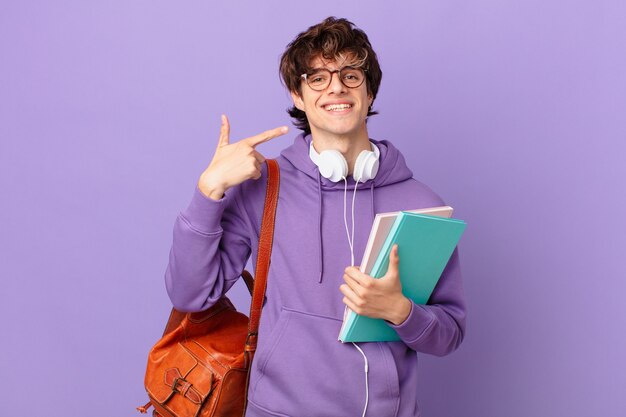 Jeune homme étudiant souriant pointant avec confiance vers son propre large sourire