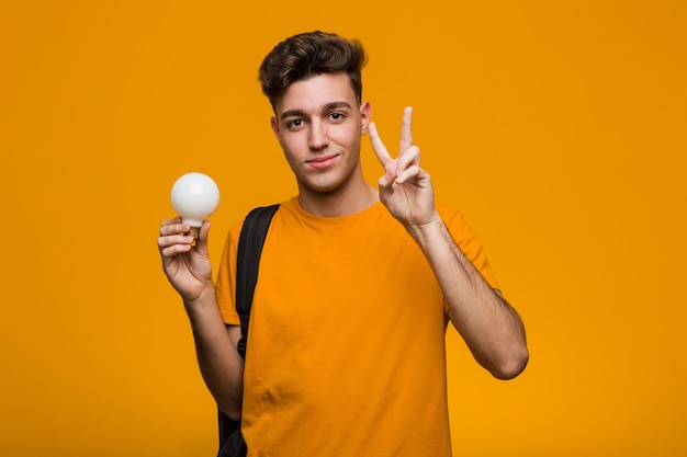 Jeune homme étudiant tenant une ampoule ayant une excellente idée