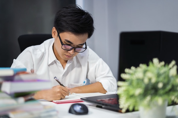 jeune homme étudie et écrit sur un ordinateur portable avec un ordinateur portable