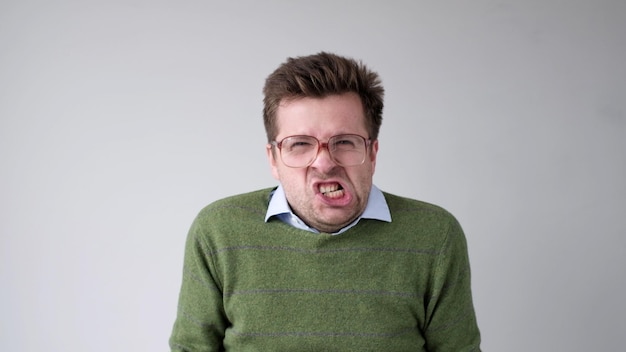 Photo le jeune homme européen n'est pas satisfait du résultat, il se met en colère et contorsionne une grimace d'aggressio