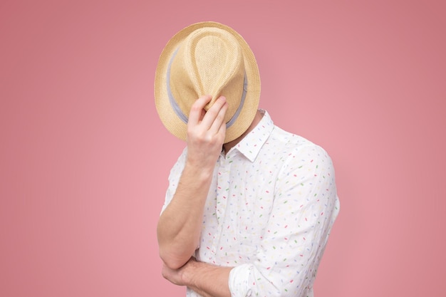 Un jeune homme européen se cache derrière son chapeau