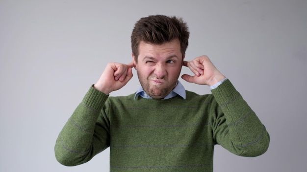 Photo le jeune homme européen se couvre les oreilles, il ne veut pas entendre la vérité inconfortable