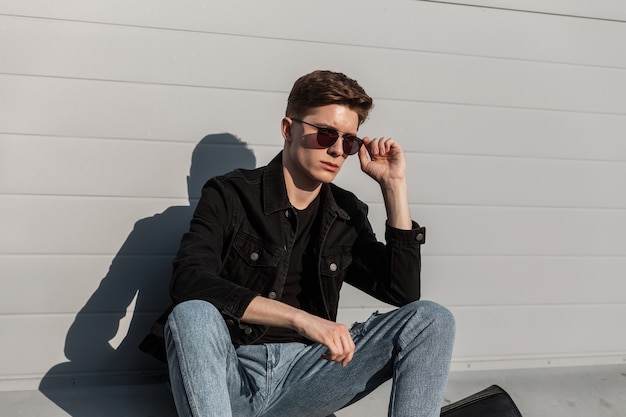 Jeune homme européen en veste en jean noir à la mode en jeans vintage