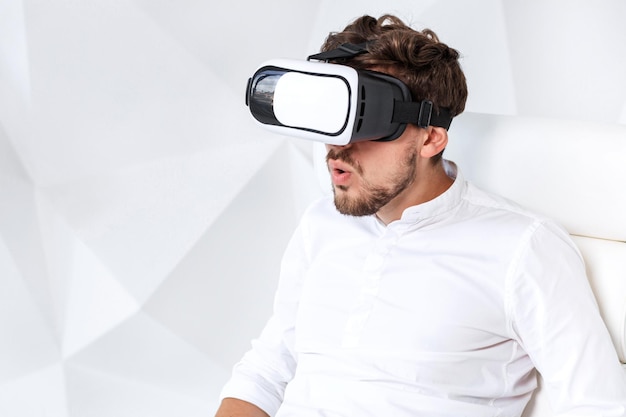 Un jeune homme excité acquiert de l'expérience en utilisant des lunettes vrheadset de réalité virtuelle gesticulant avec l'esprit ...