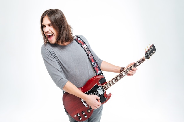 Jeune homme excité fou criant et jouant de la guitare électrique sur fond blanc