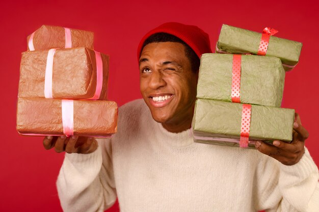 Un jeune homme excité à la peau foncée avec des coffrets cadeaux dans les mains