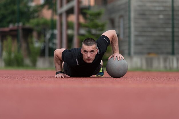 Jeune homme exécutant des pompes à l'extérieur sur l'exercice de musculation Medicine Ball