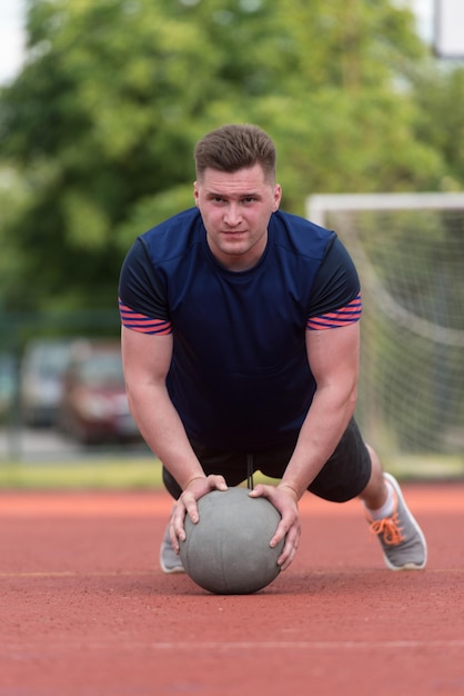 Jeune homme exécutant des pompes à l'extérieur sur l'exercice de musculation Medicine Ball