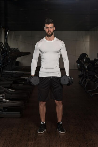 Jeune homme exerçant des biceps avec des haltères Curls de concentration d'haltères