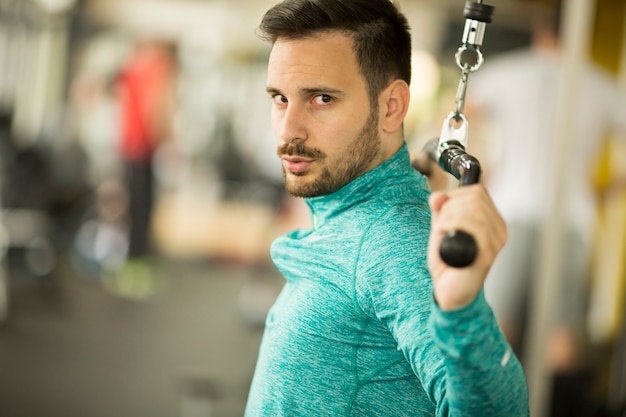 Jeune homme exerce sur un appareil d&#39;exercice au gymnase