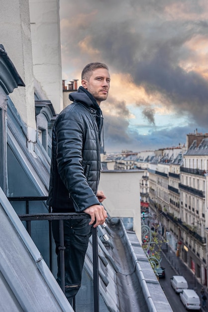 Jeune homme explorant les rues étroites de Paris depuis un balcon en France.