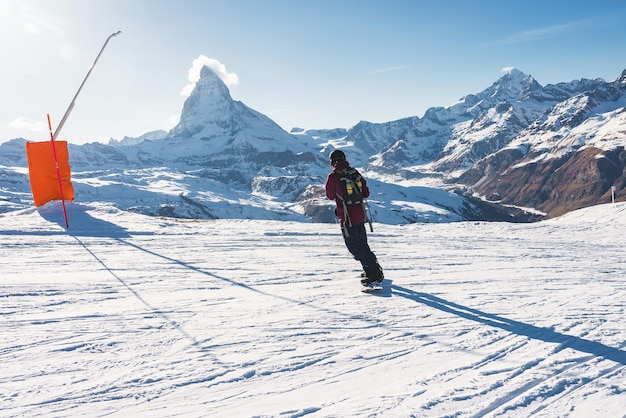Jeune homme faisant du snowboard dans la station de ski de zermatt juste à côté du célèbre pic du cervin