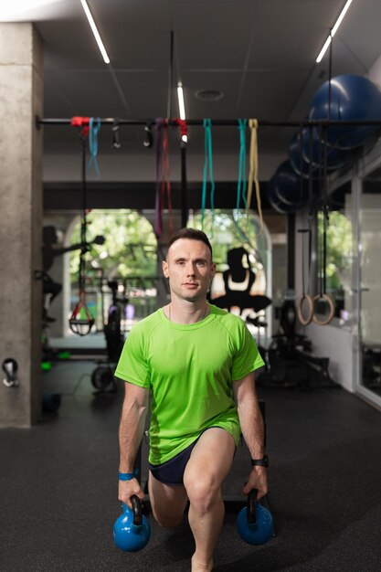 Un jeune homme faisant du split squat et tenant les kettlebells