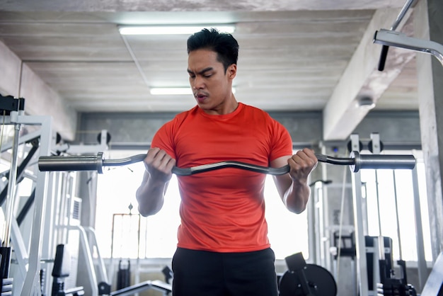 Photo jeune homme faisant de l'exercice dans la salle de gym soulever des poids améliorant la santé renforcer les muscles pour la force concept d'exercice