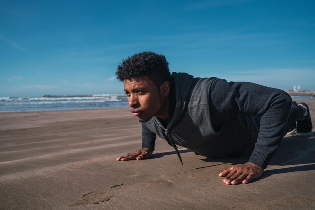 Un jeune homme faisant de l'exercice sur la plage contre le ciel