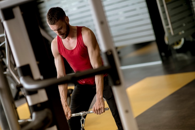 Jeune homme faisant des exercices pour le dos avec machine d&#39;exercice dans un club de gym