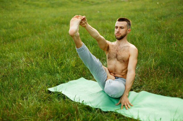 Jeune Homme Faisant La Pose Du Bateau Pendant La Pratique Du Yoga Dans Le Parc