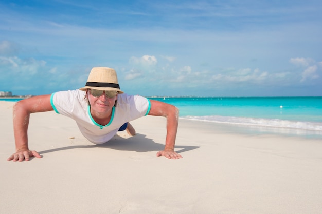 Jeune homme faisant des push ups sur une plage parfaite