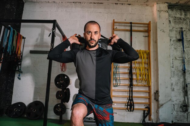 Jeune homme faisant des squats avec des poids