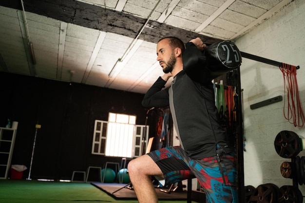 Jeune homme faisant des squats avec des poids