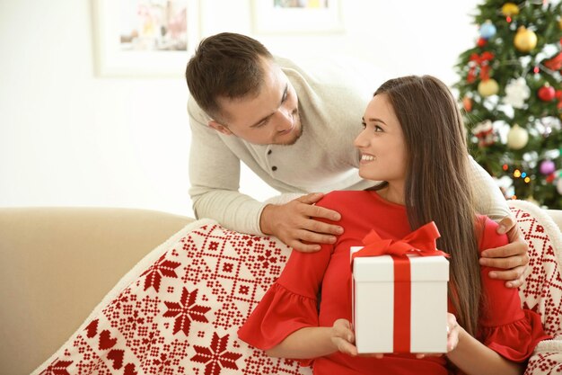 Jeune homme faisant une surprise de Noël pour sa petite amie à la maison