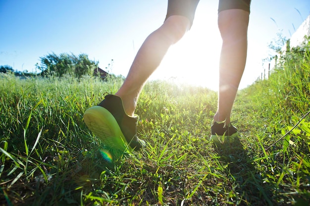 Un jeune homme fait du jogging à travers le pays à travers le sentier dans le pré