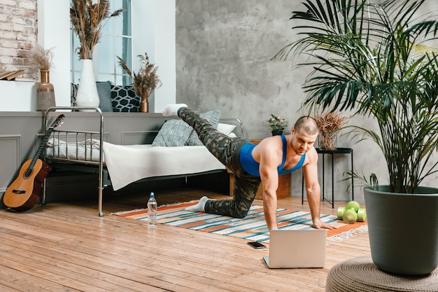 Le jeune homme fait du sport à la maison