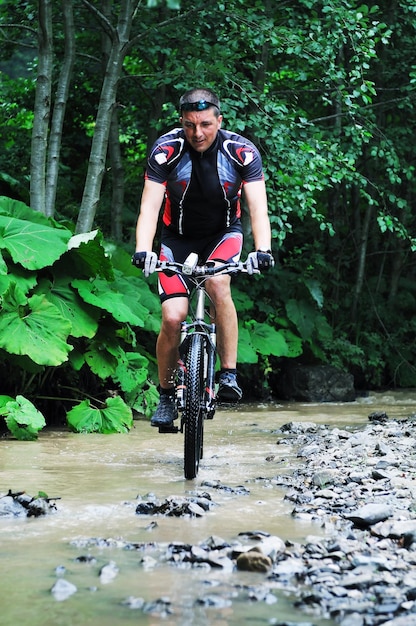 Un jeune homme fait du vélo de montagne sur une rivière.