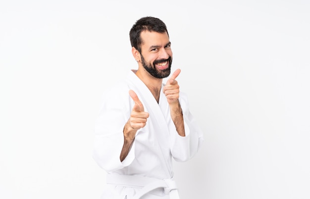 Jeune homme fait karaté sur blanc isolé pointant vers l'avant et souriant